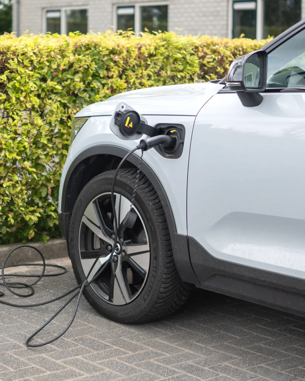 Elektrische auto laadt op een oprit, met de laadkabel in de laadklep